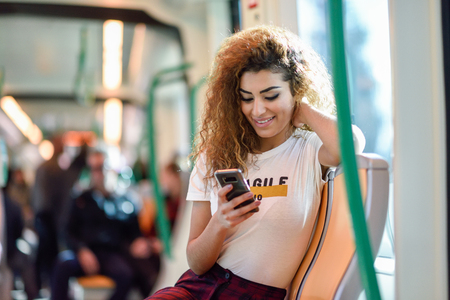 woman looking at her phone and smiling while riding on public bus