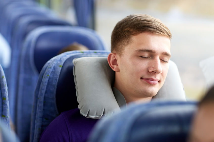 man comfortably sleeping on coach bus
