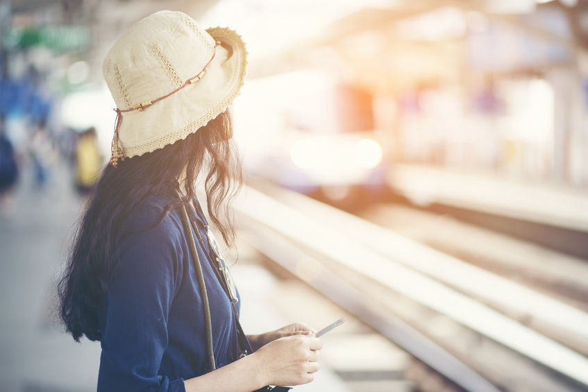 Woman waiting outside bus station in the summer sun