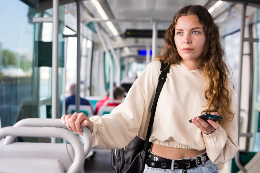 Portrait of a thoughtful girl with a mobile phone in her hands, riding in a tram