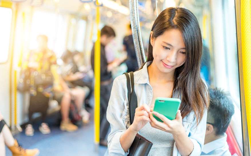woman looking down at cell phone on public transport