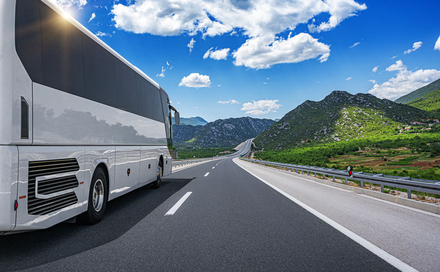 Passenger bus on the highway against the backdrop of a beautiful summer landscape.