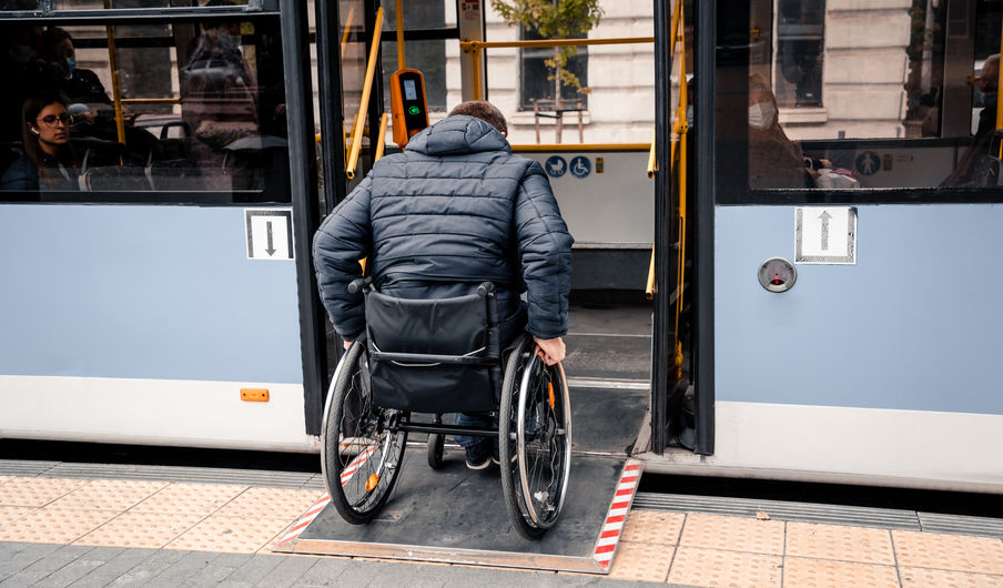Person with a physical disability enters public transport with an accessible ramp